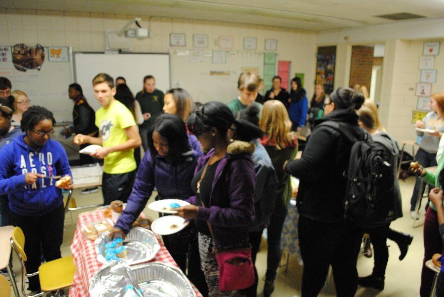 French club members huddle around food tables, preparing to celebrate.