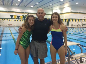 Junior Gina Peruzzi, varsity assistant swimming coach  Fred Michalik and freshman Olivia Peruzzi pose for a family photo in front of the pool.