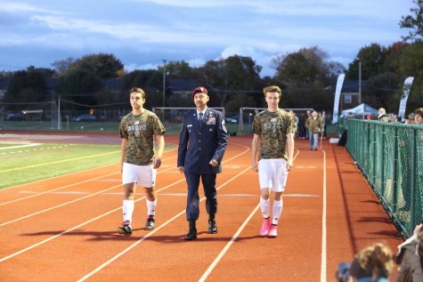 Junior Kevin Topciu and sophomore Dylan Watts escort a veteran down the track in the game's opening procession. 