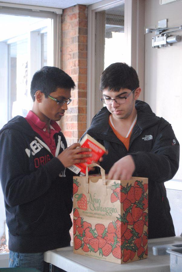 Senior Jay Garlapati works with junior Vince Alibri to place books in a bag. (Photo by Gabby Tatum)