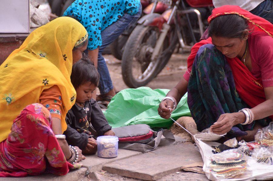 Two children and their mothers work on the ground in the market.