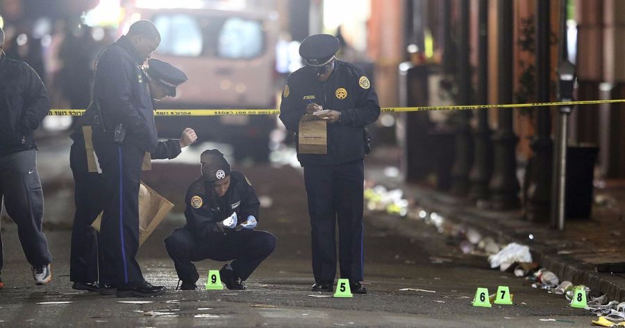 Detectives and policemen investigate the crime scene in New Orleans where one person died and nine others were wounded. 