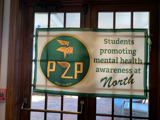 NEW YEAR, SAME BANNER| During the retreat, the banner made for the suicide prevention walk in May 2022 appeared in the doorway of the conference room at Pier Park. Social worker and Peer 2 Peer advisor Kelly Osborne assisted the club’s members in creating Peer 2 Peer’s campaigns.  “Our 26 student members are responsible for creating our yearly slogan and campaign,” Osborne said.

