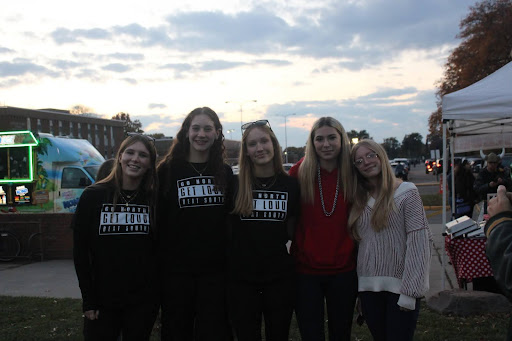 JOINING TOGETHER | Despite supporting opposing teams, two groups of high school students are able to find common ground at the tailgate before the intense game. North sophomore Rose Parker (to the left of the center) stands beside her South sophomore peer Mia Labadie (right). “This was my second tailgate, and I came to hang out with my friends and enjoy the activities for the whole community,” Parker said. “I enjoyed it and thought it was fun.”
